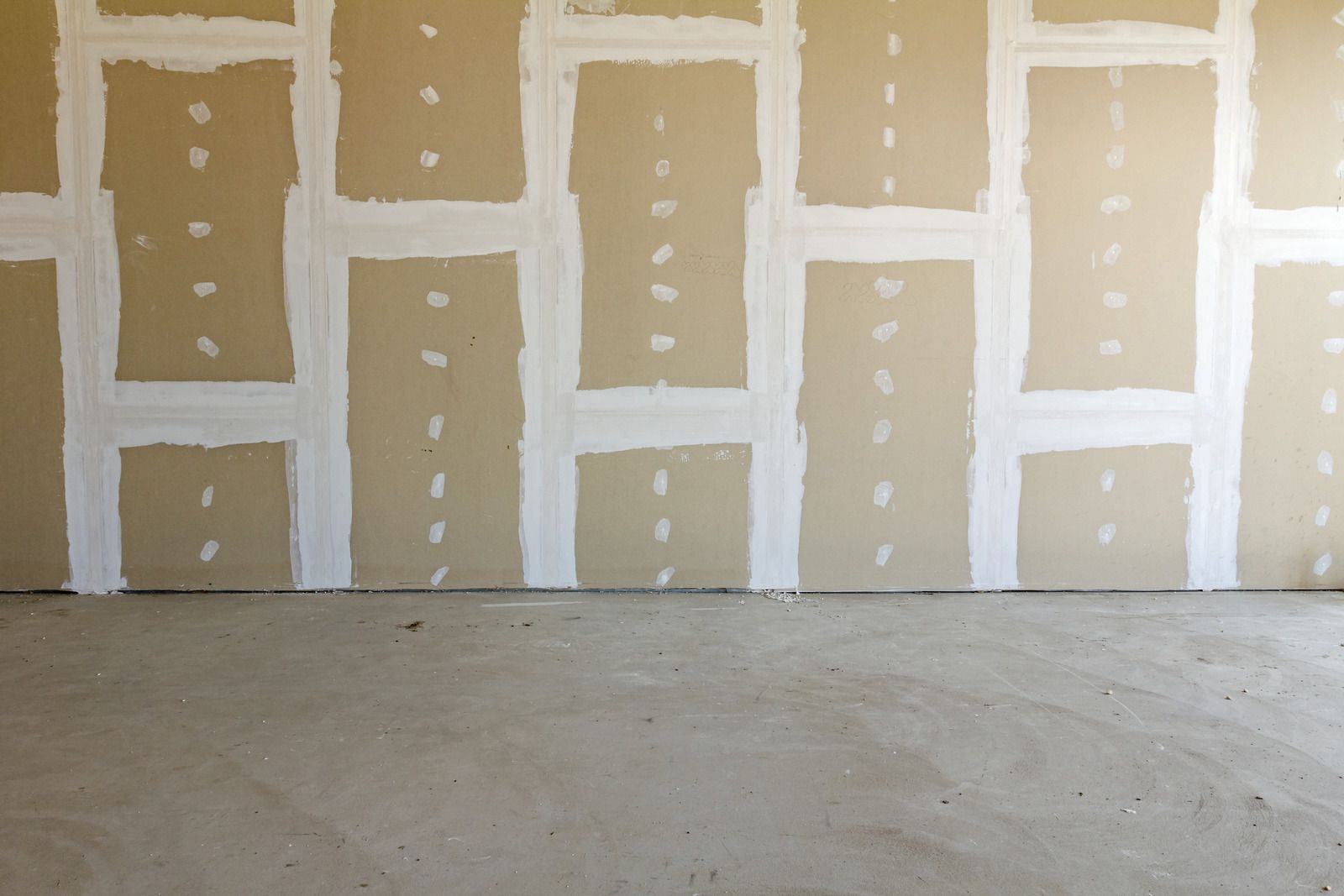 Drywall with white joint compound and concrete floor.