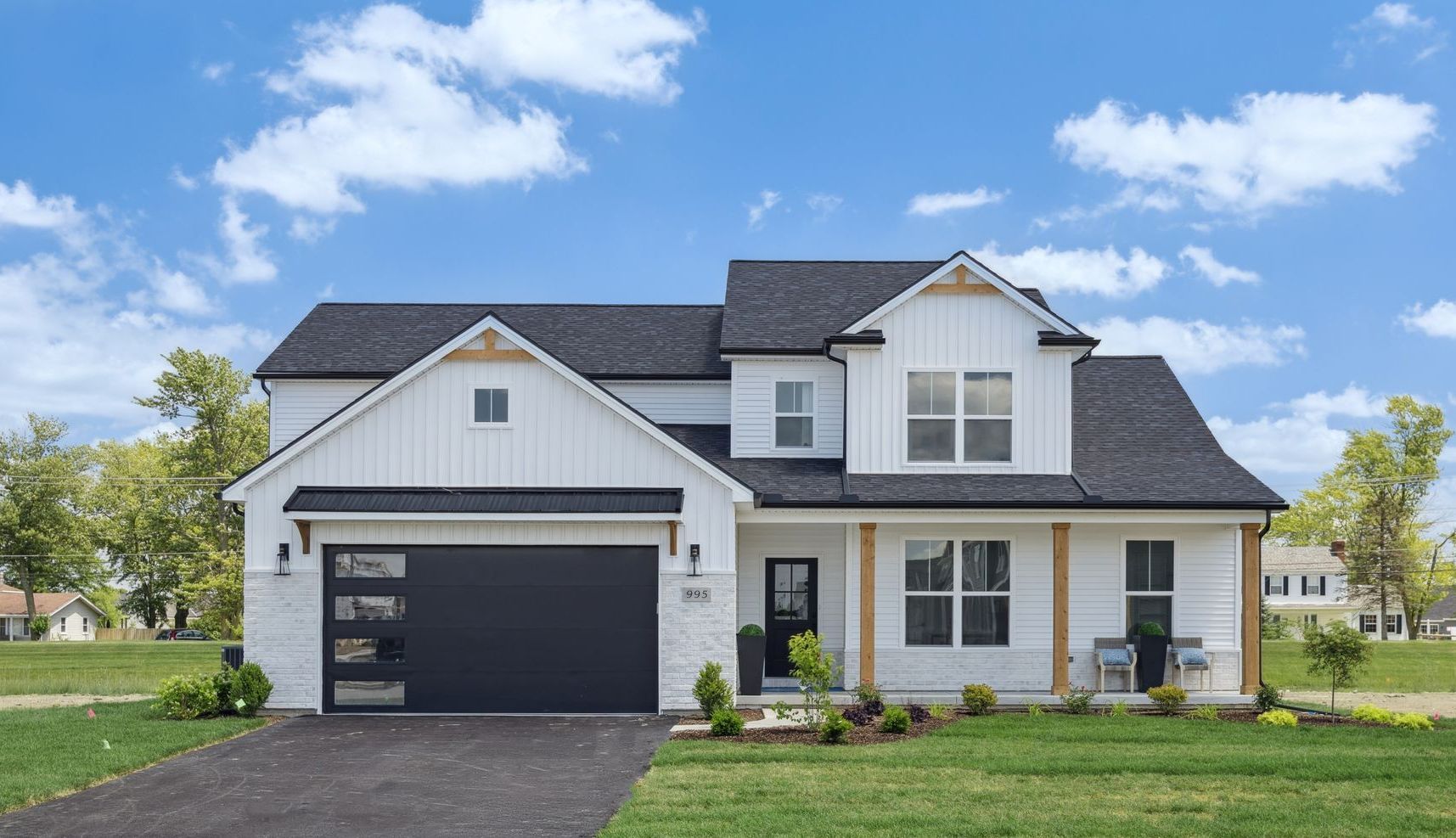 A white house with a black garage door and a black roof.