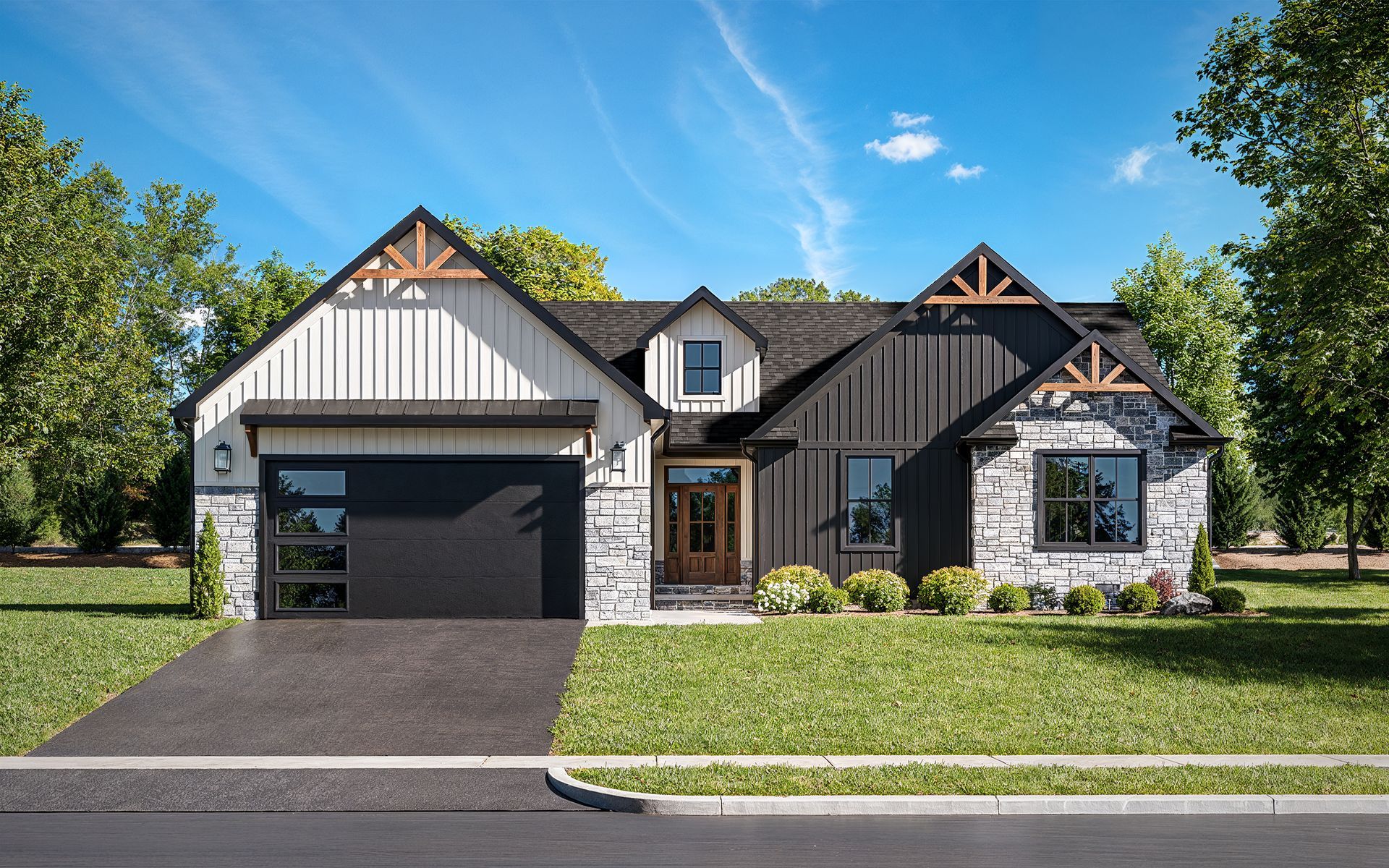 A white house with a black garage door and a black roof.