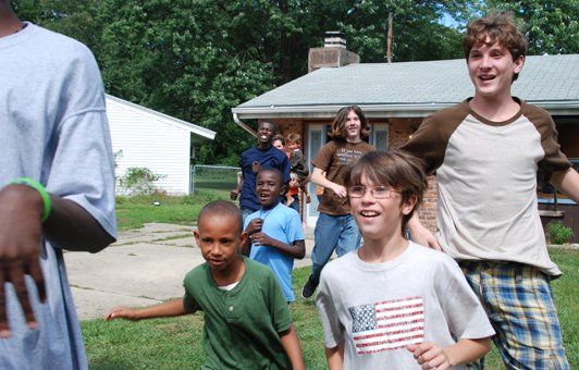 A boy wearing an american flag shirt is running with other children