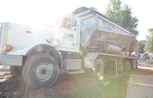 A white dump truck is parked on the side of the road.