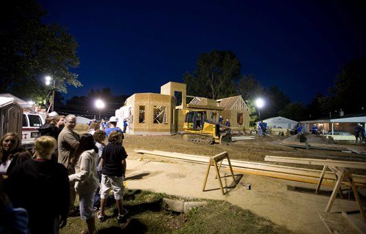 A group of people are standing in front of a building under construction at night.