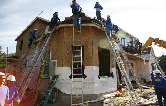 A group of construction workers are working on a house