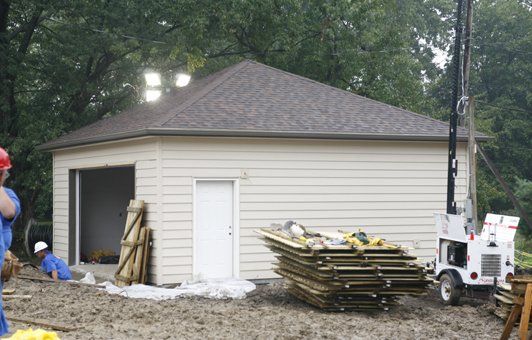 A man in a hard hat is standing in front of a building under construction.
