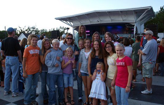 A group of people are posing for a picture and one of them is wearing a shirt that says wrangler