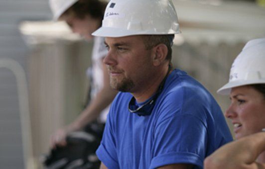 A man wearing a blue shirt and white hard hat