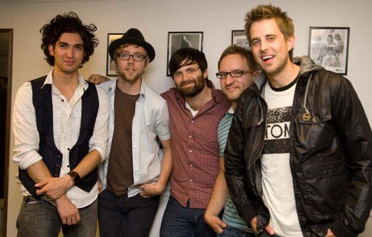 A group of men posing for a picture with one wearing a shirt that says ton