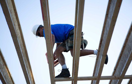 A man in a hard hat is working on a wooden structure.