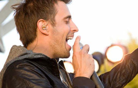 A man in a leather jacket is singing into a microphone.