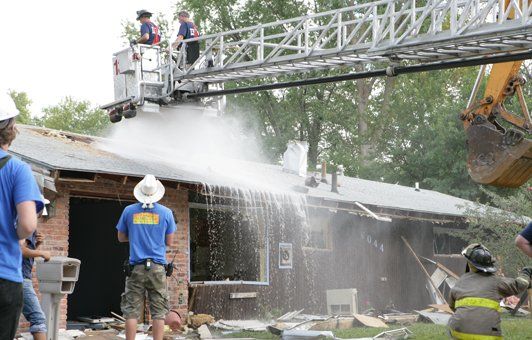 A group of people are spraying water on a house.
