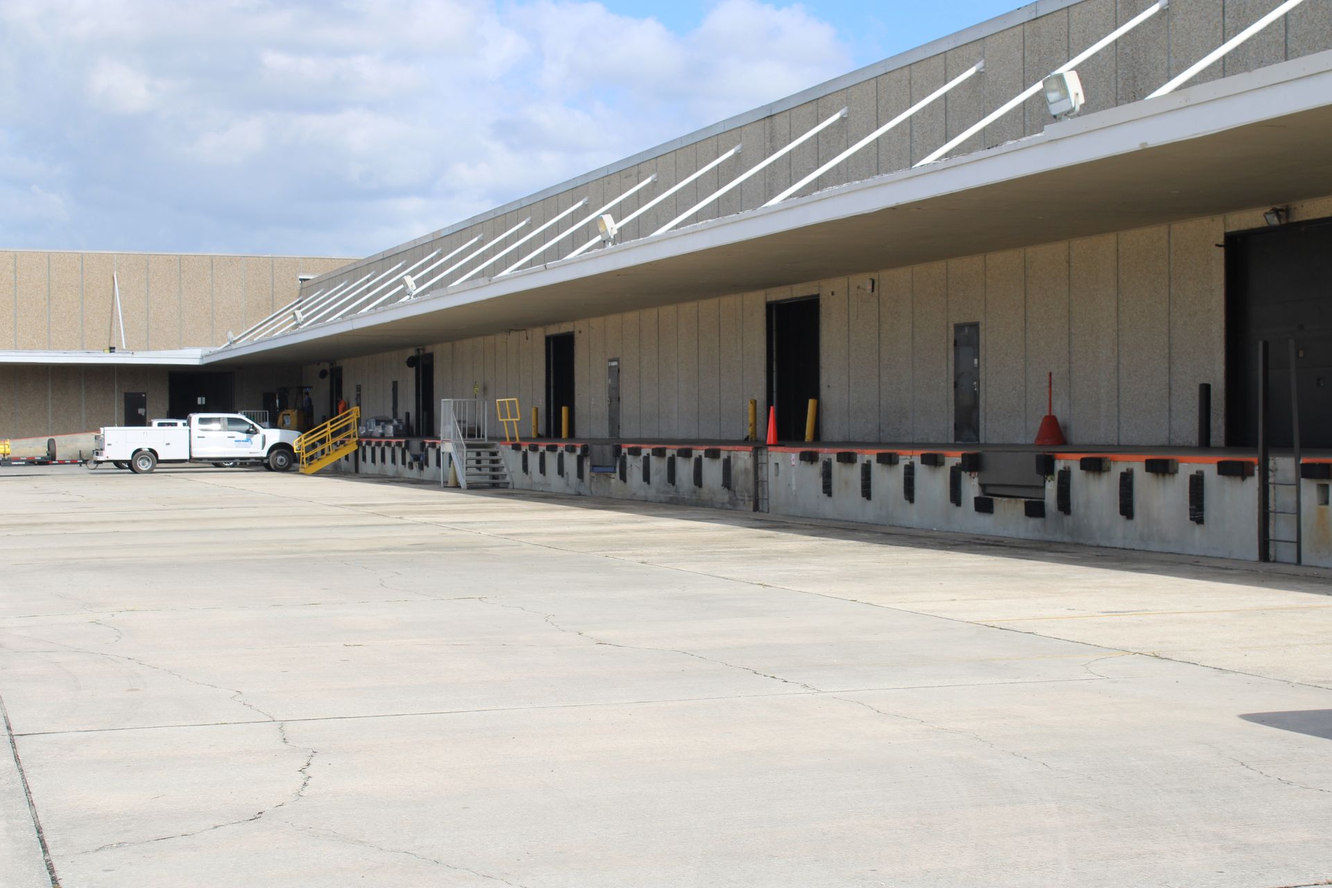 A white truck is parked in front of a large warehouse.