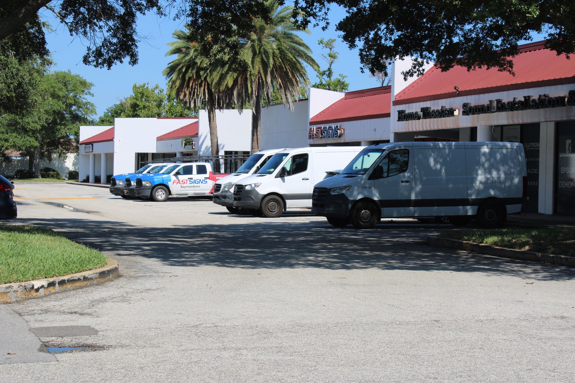 A row of white vans are parked in front of a building