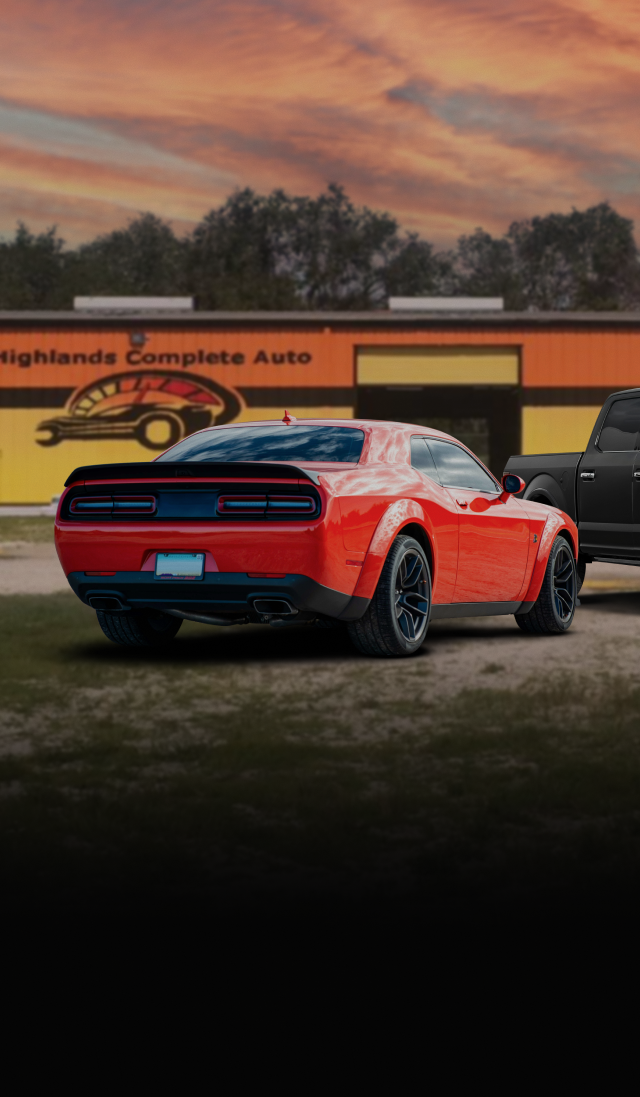 Red Dodge Challenger parked in front of Highlands Complete Auto garage at sunset. | Highlands Complete Auto
