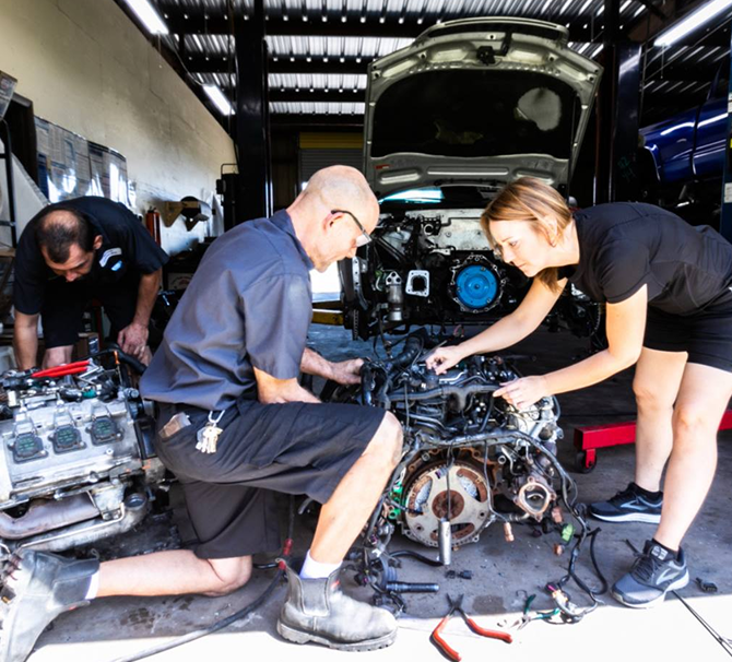 Three mechanics working on car engines in a repair shop. | Highlands Complete Auto