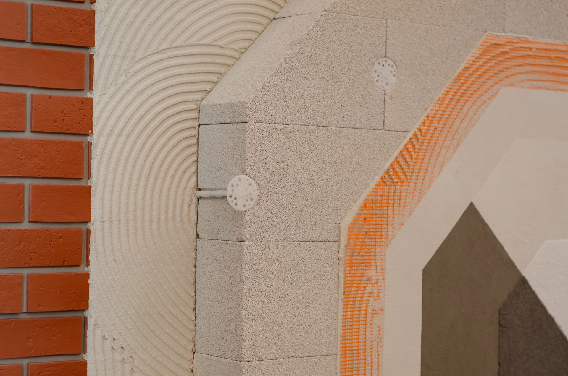 Vista in sezione della costruzione del muro esterno che mostra gli strati di mattoni, isolamento e intonaco.