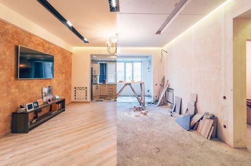 Vista divisa di un soggiorno: lato finito con TV e mobili; lato grezzo con materiali da costruzione.