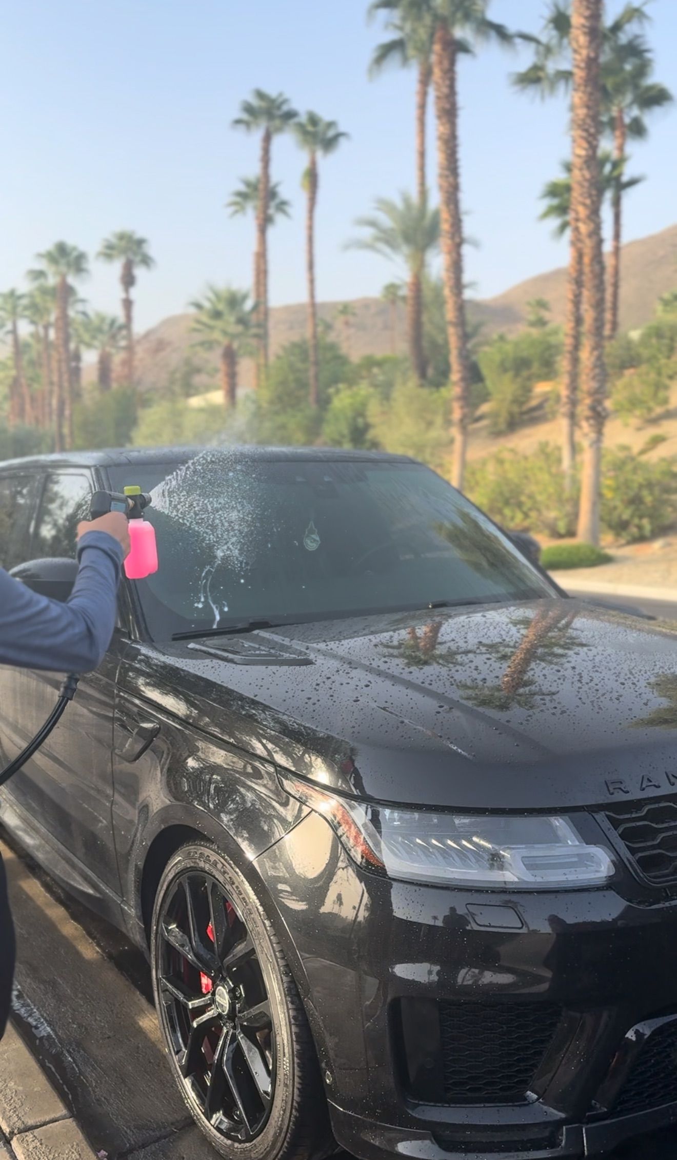 Person vacuuming a car's interior, cleaning the black seat with a yellow nozzle.