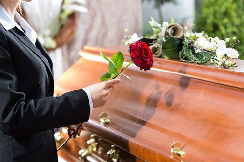 persona mette una rosa sulla bara durante un funerale