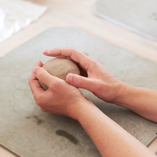 Hände formen eine Kugel aus Ton