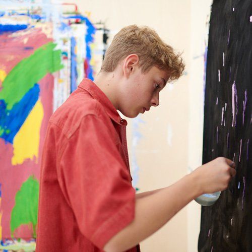 Jugendlicher malt ein Bild im KunstTherapieRaum