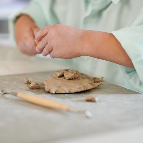 Kleiner Junge formt ein Objekt aus Ton