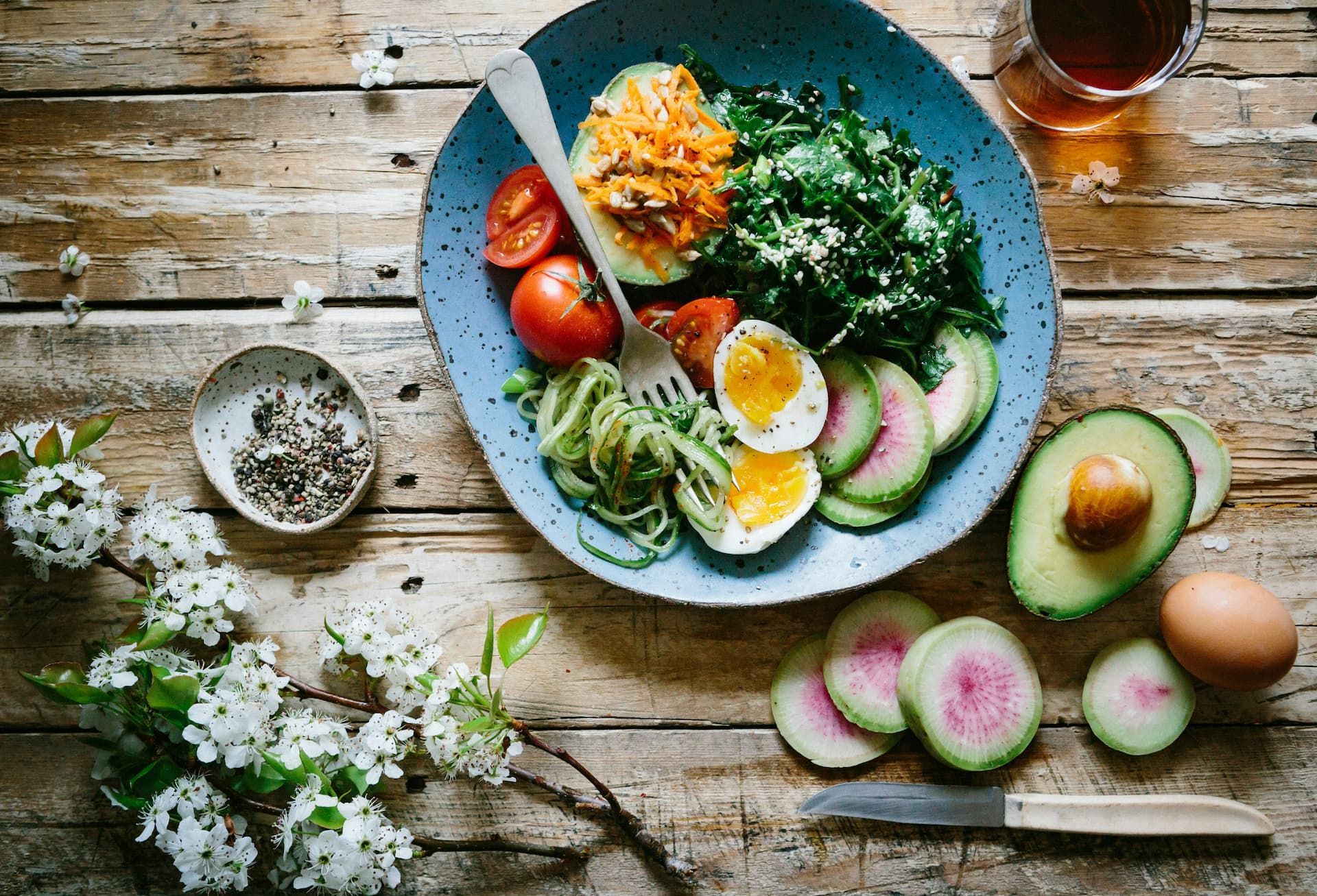 A plate of food with eggs , avocado , and tomatoes on a wooden table.