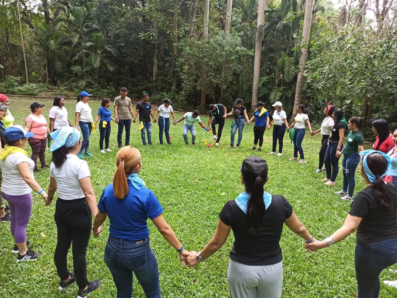 Un grupo de personas están de pie en un círculo tomadas de la mano.