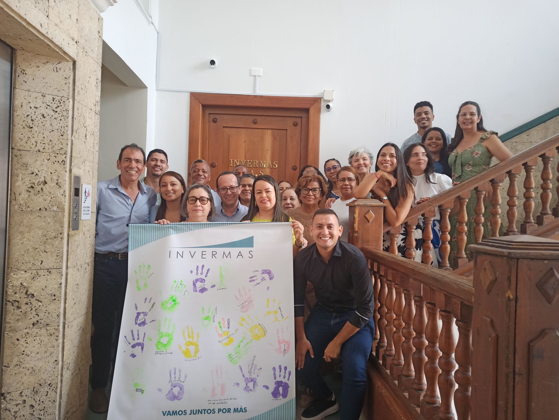 Un grupo de personas posa para una fotografía mientras sostiene un cartel que dice 