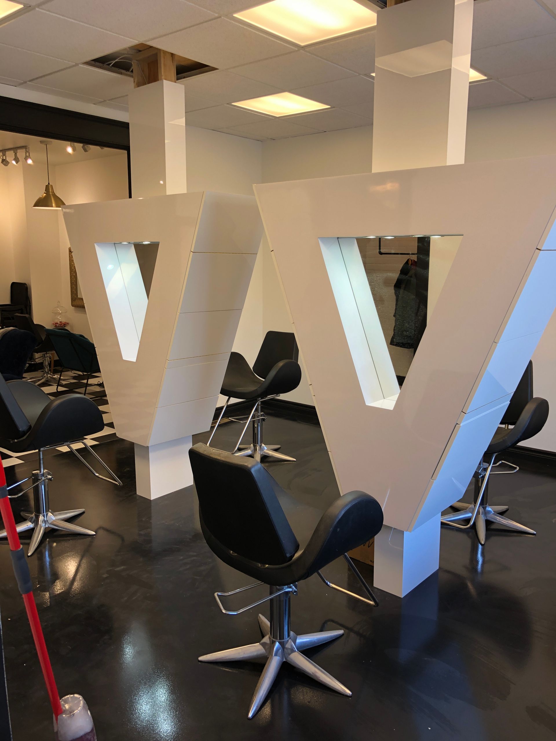 Un salon avec des chaises et une grande lettre v au mur