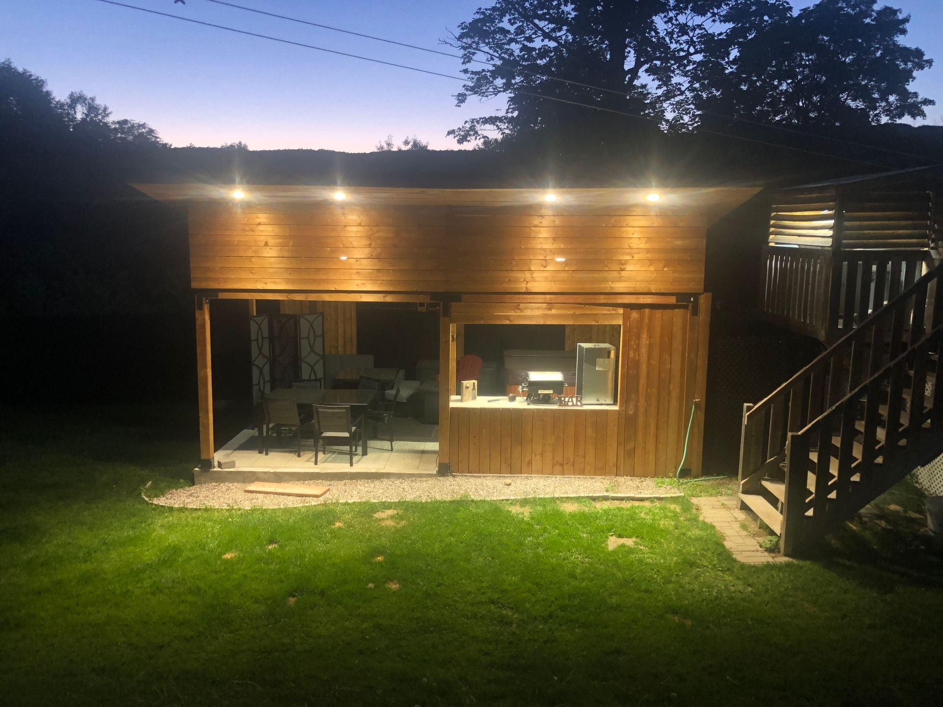 Un bâtiment en bois avec des escaliers qui y mènent est éclairé la nuit