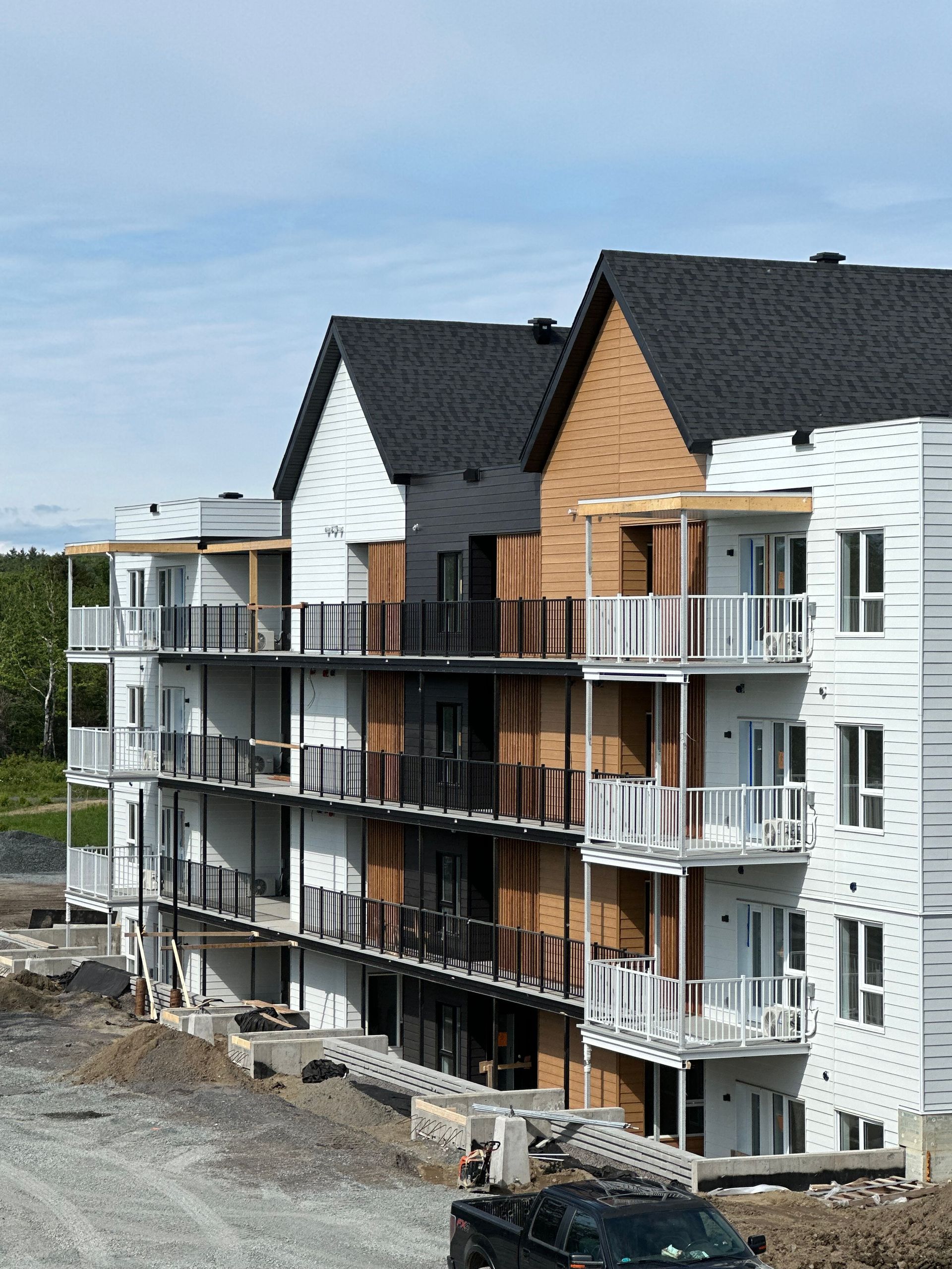 Un grand immeuble en construction avec un camion noir garé devant lui