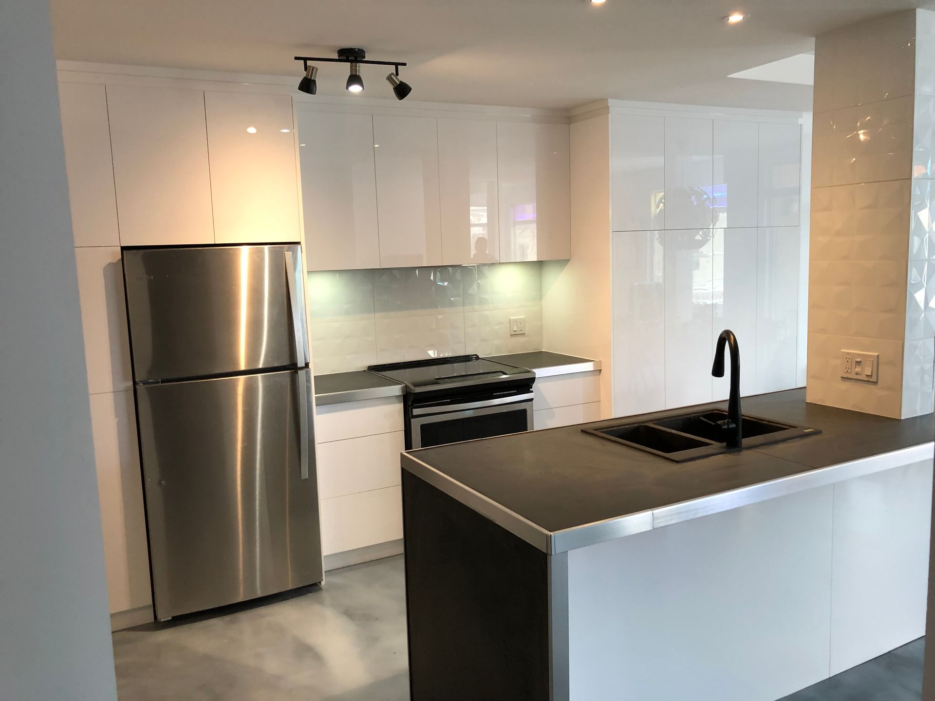 Une cuisine avec des appareils électroménagers en acier inoxydable et des armoires blanches