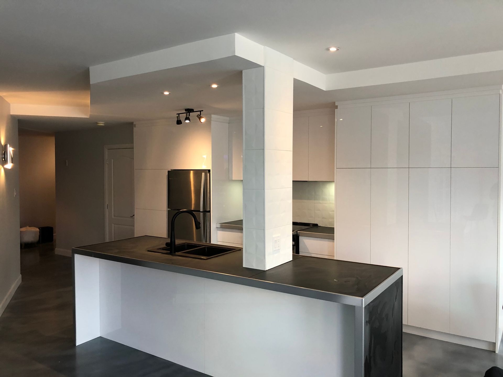 Une cuisine avec des armoires blanches et un comptoir noir.