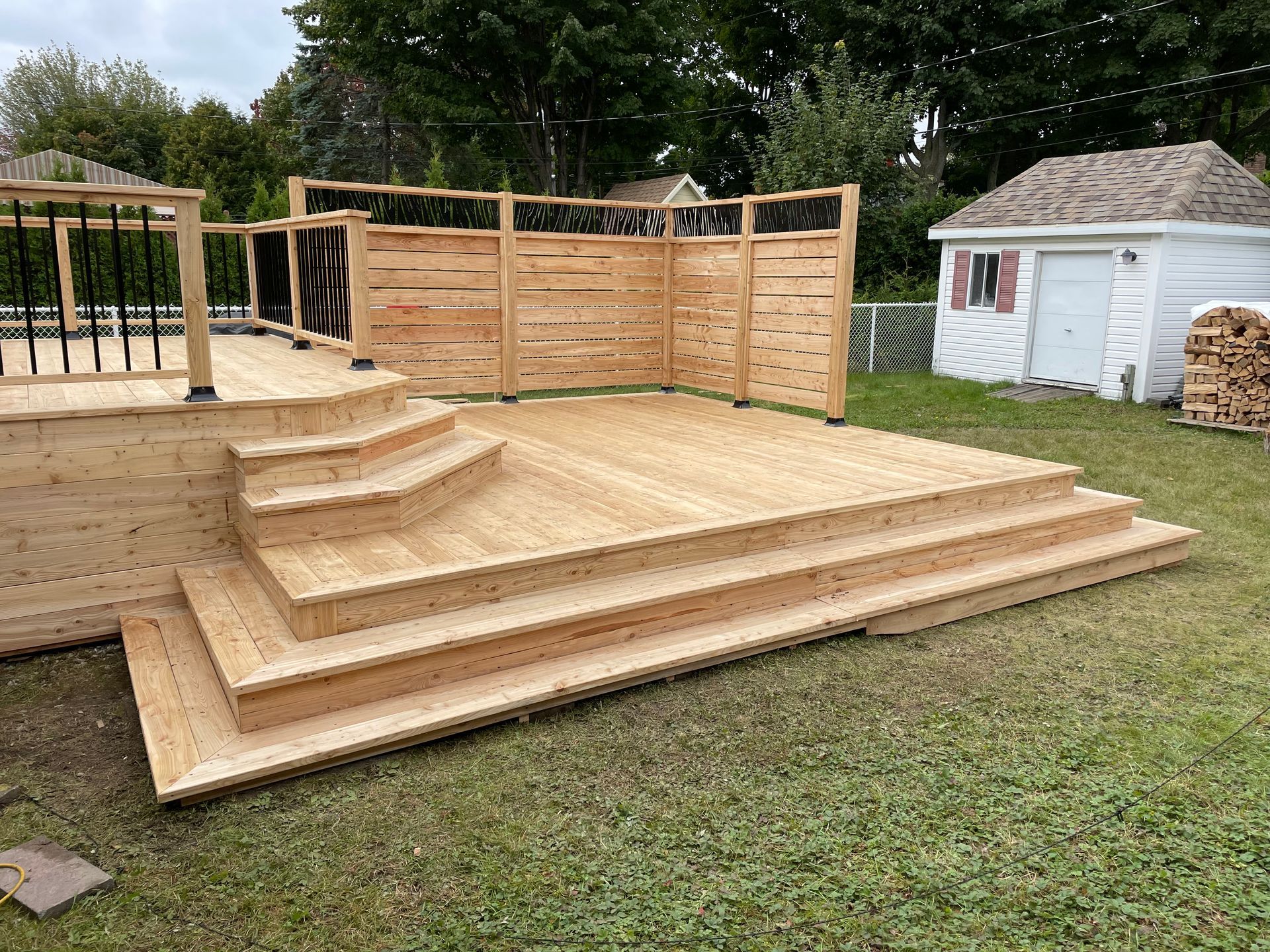 Une terrasse en bois avec des escaliers et une clôture dans une cour.