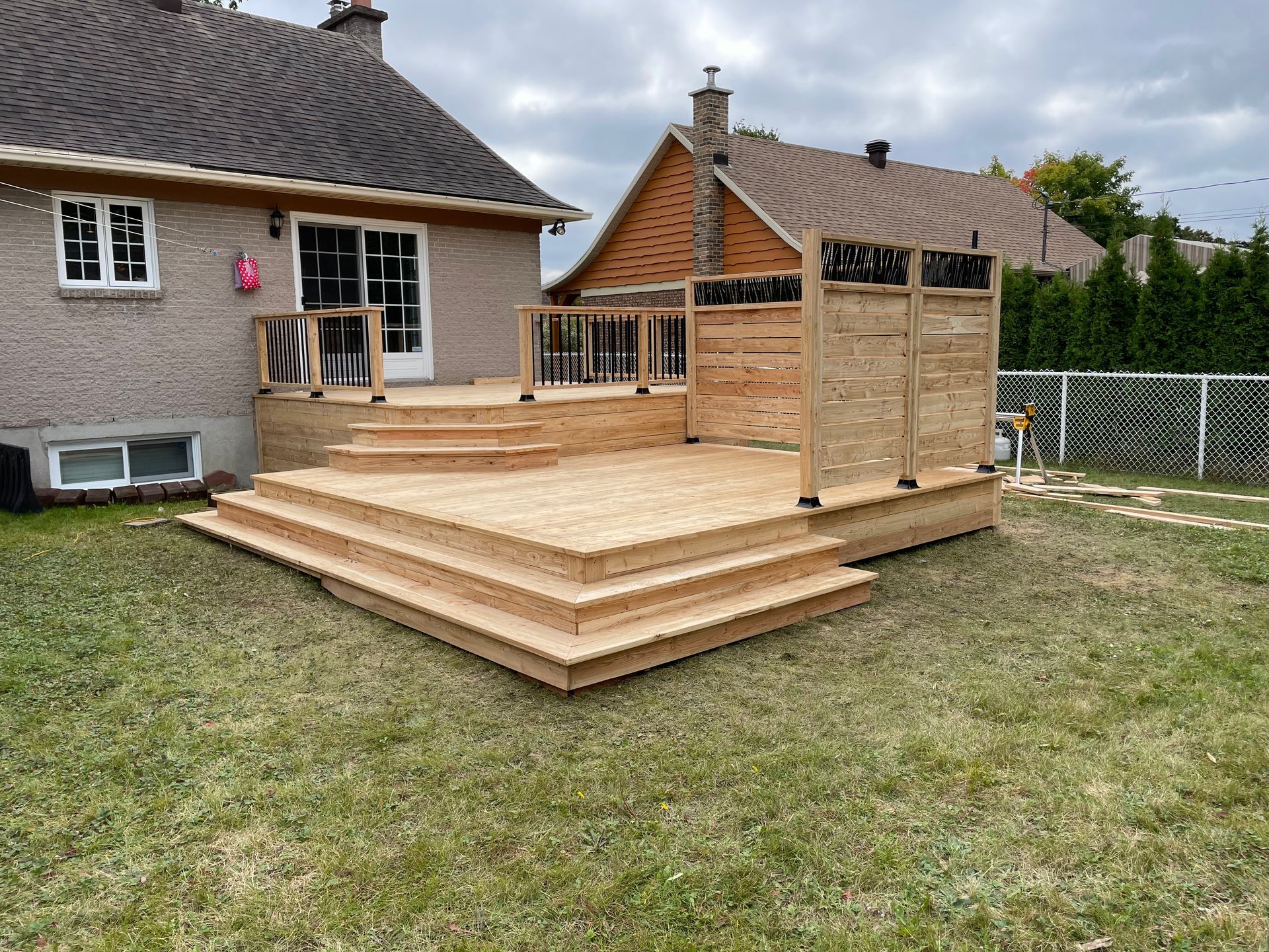 Une terrasse en bois avec des escaliers se trouve dans la cour d'une maison.