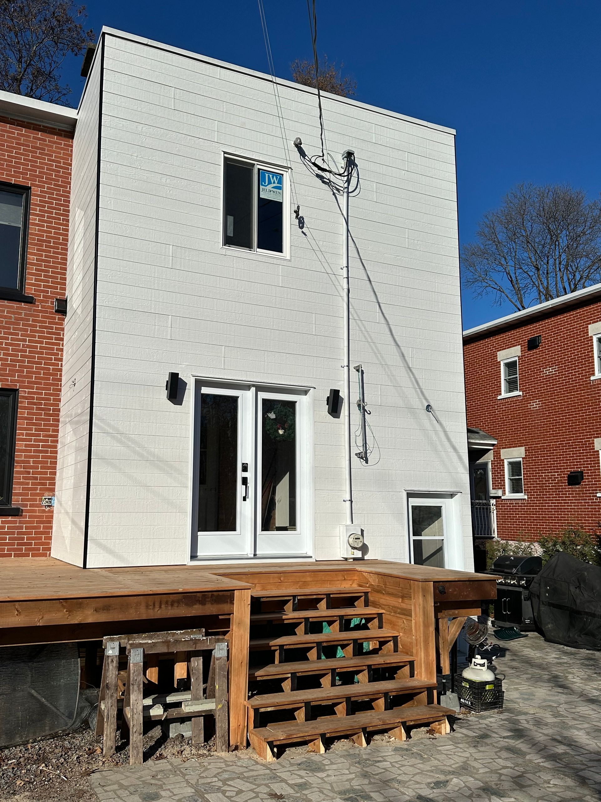 Une maison blanche avec une terrasse en bois devant.
