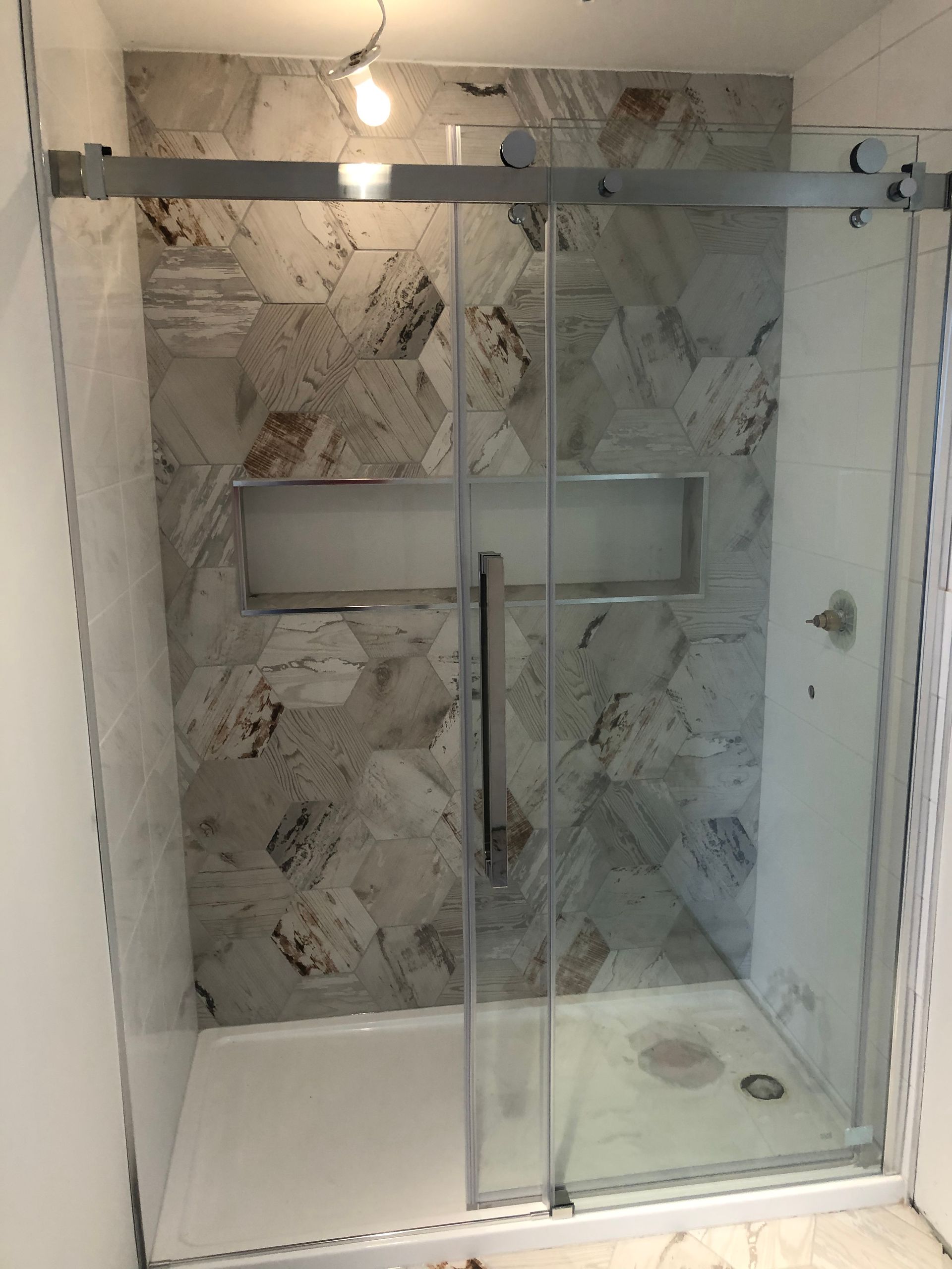 Une cabine de douche avec porte coulissante en verre dans une salle de bain.