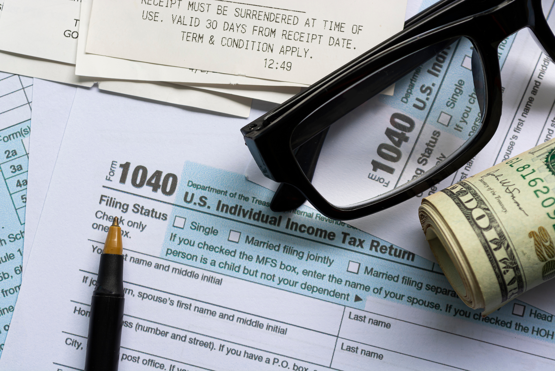 A pen and glasses are on top of a 1040 tax form