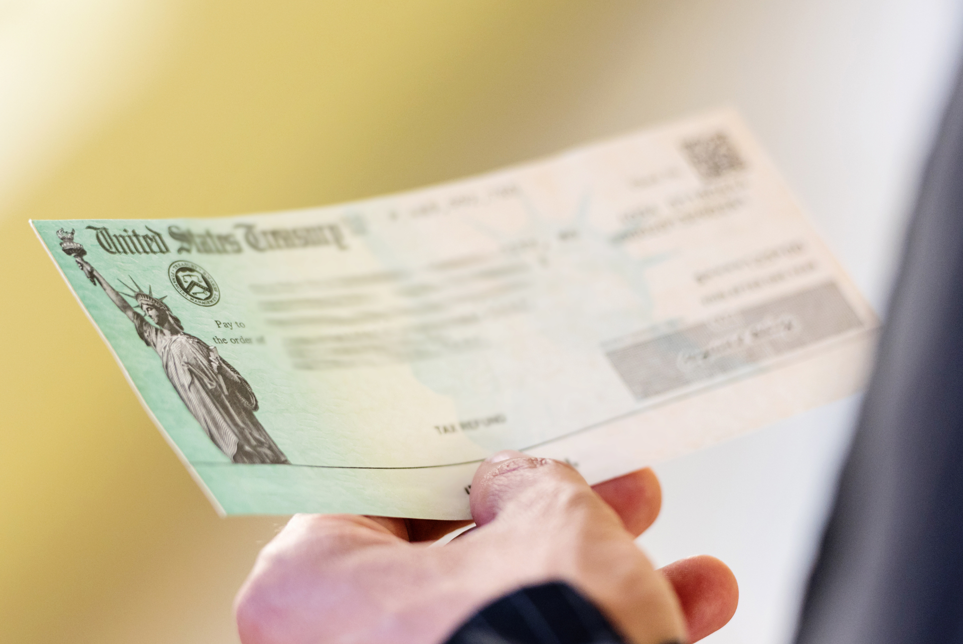 A person is holding a check with the statue of liberty on it.