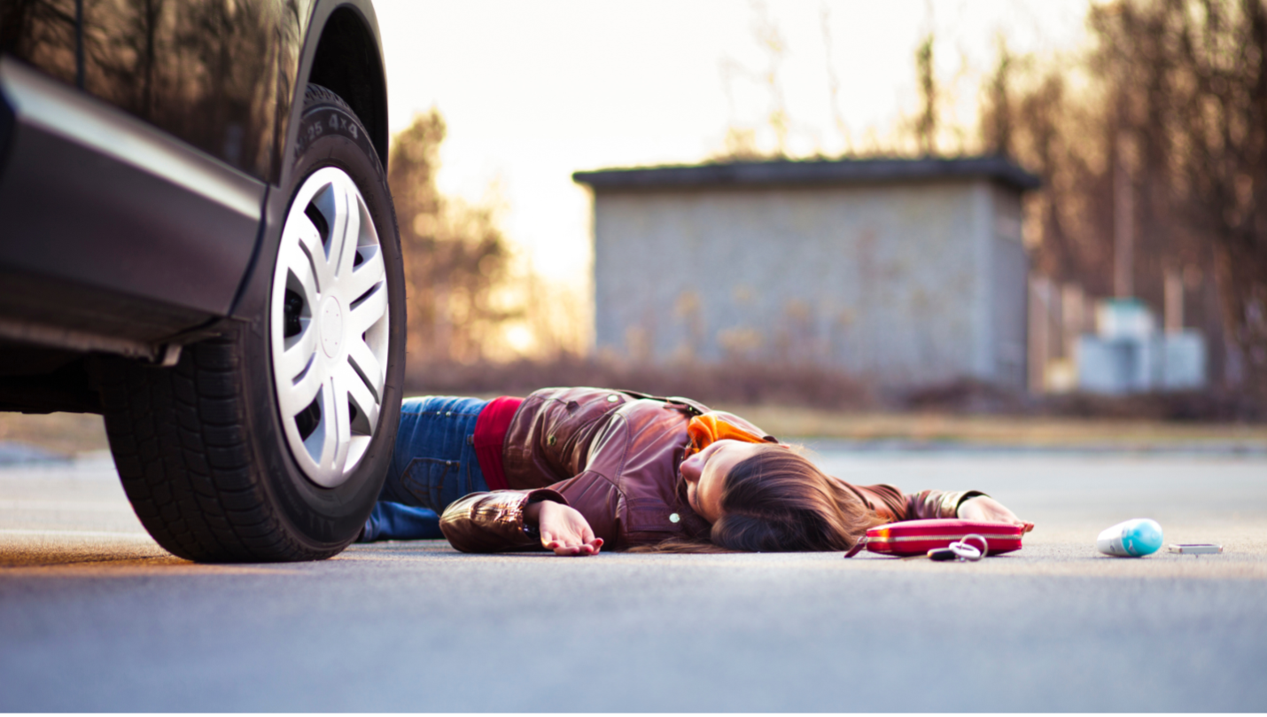 woman on ground in front of car