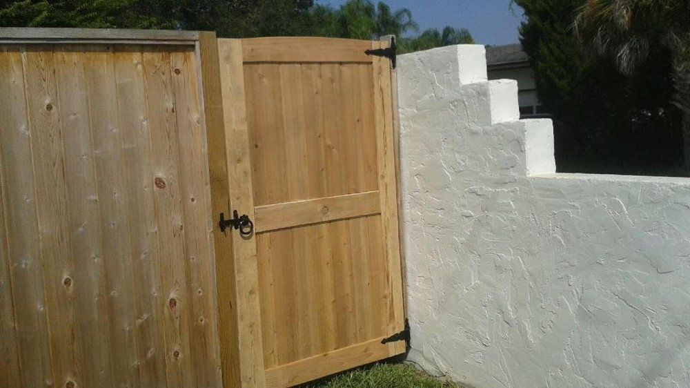 Wooden gate beside a white stucco wall in a sunny yard