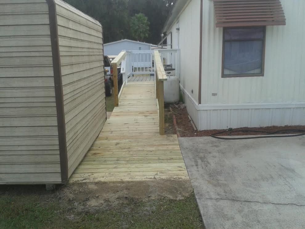 Wooden ramp walkway between mobile homes leading to a fenced area.