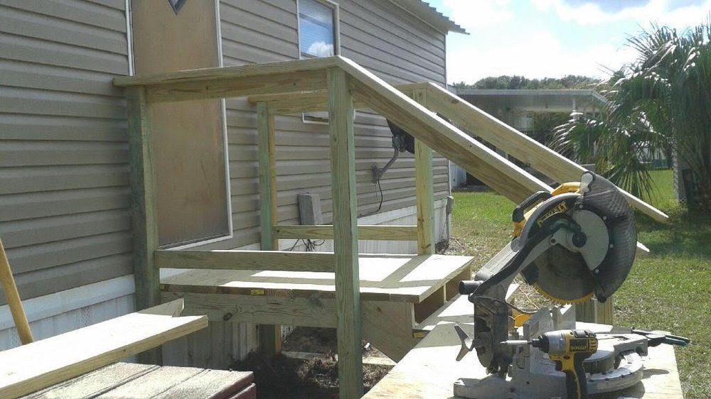 Person using a drill to install a drawer slide in a wooden cabinet.