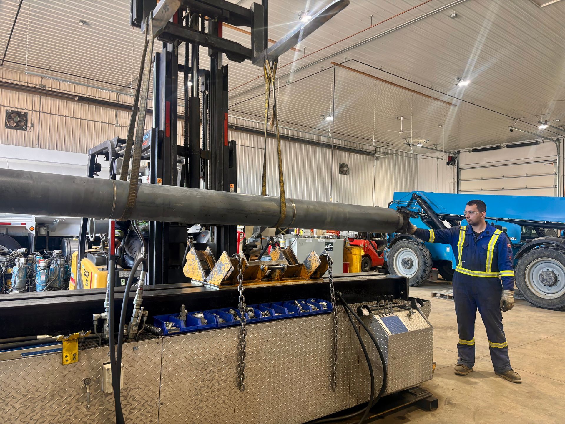 A bunch of hydraulic cylinders are sitting on pallets in a warehouse.