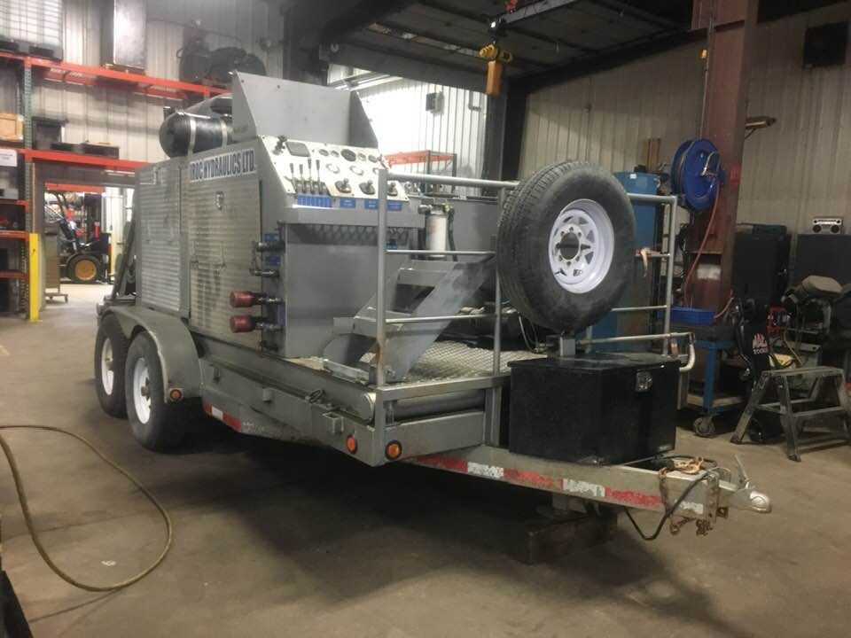 A large yellow hydraulic cylinder is sitting on a wooden pallet.