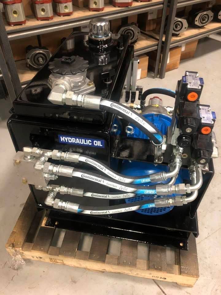 A forklift is sitting in a garage next to a pallet of hydraulic cylinders.
