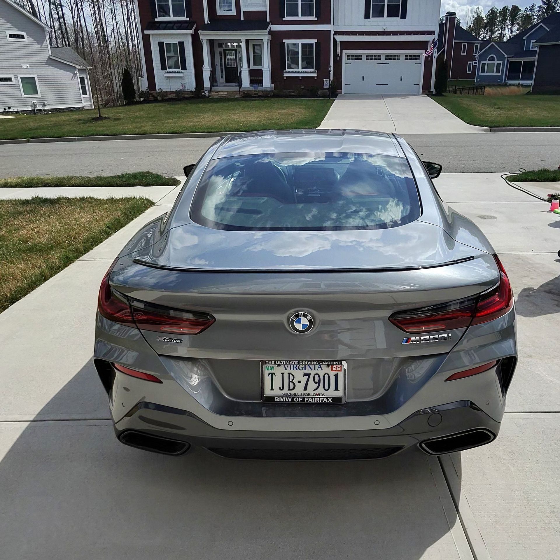 Gray BMW 8-series coupe parked on a driveway in front of a house.