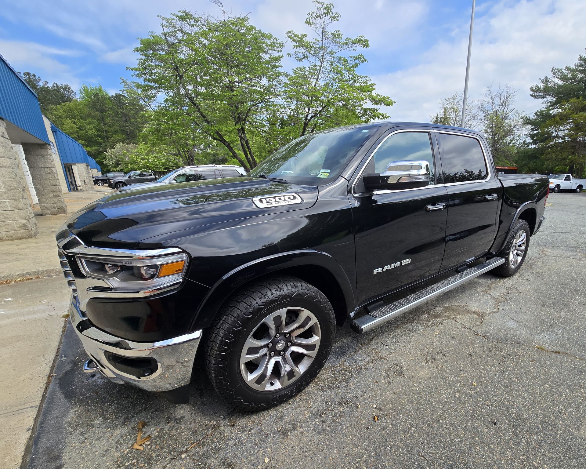 Black Ram pickup truck parked on pavement in front of a building on a sunny day.