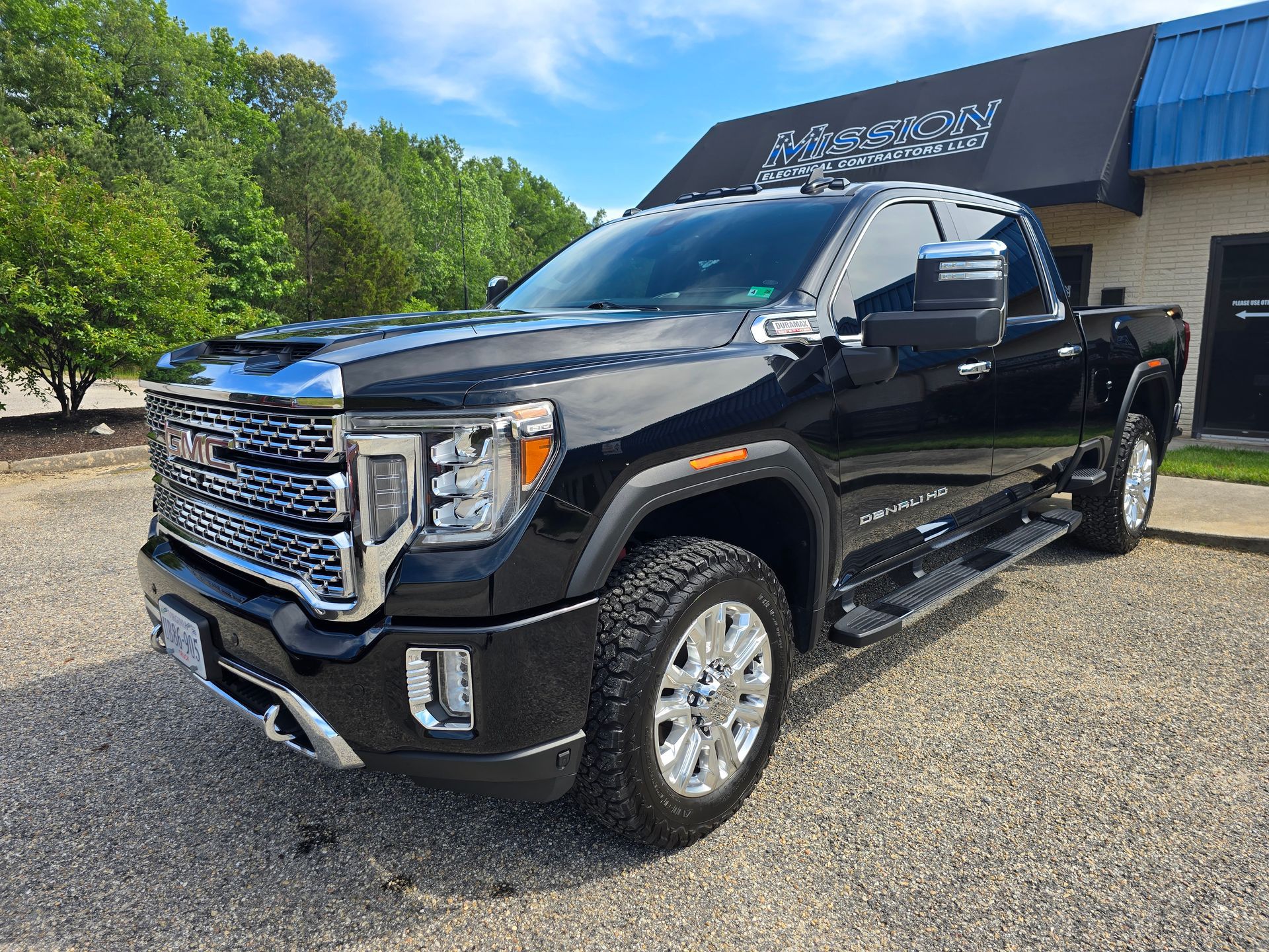 Black GMC pickup truck parked in front of a building with a blue awning.