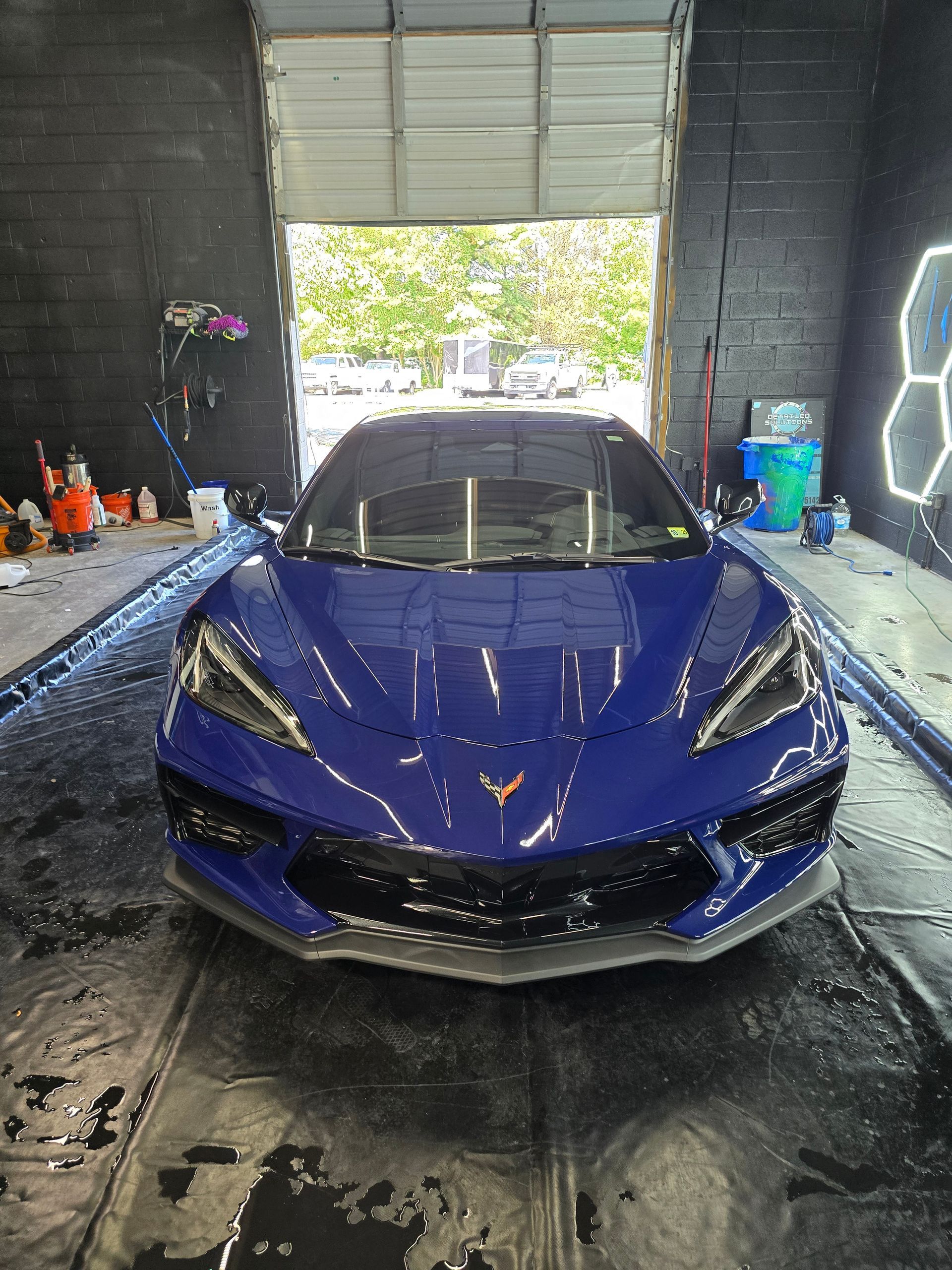 Blue sports car in a car wash, standing under an open doorway.